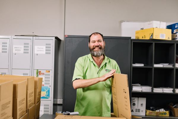 Worker smiling and holding flattened cardboard box