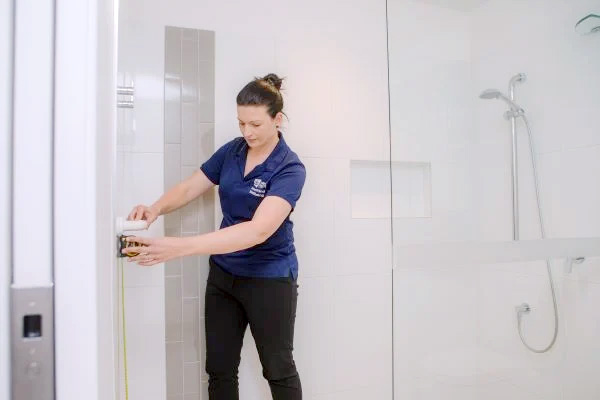 Therapist using tape measure to measure height of grab rail in bathroom