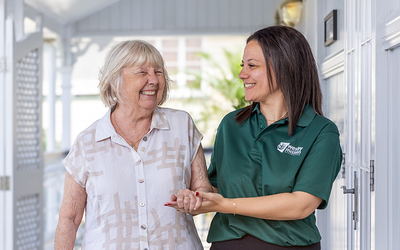 Home care worker smiling as she chats with a happy client at her Queenslander home