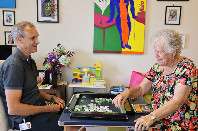 Mark, a volunteer, plays Mahjong with Catie, a Home Care Package client