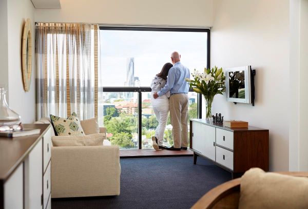 Couple enjoying expansive views of Brisbane skyline from an apartment at Aldersgate retirement village, in Red Hill, Brisbane