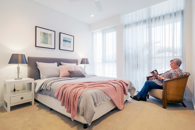 Lady reading a book in her bedroom in Rosemount retirement apartments