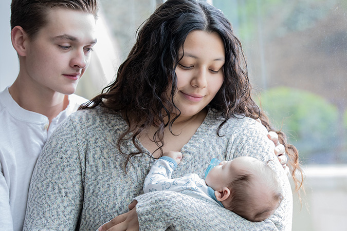 Very young parents holding a baby